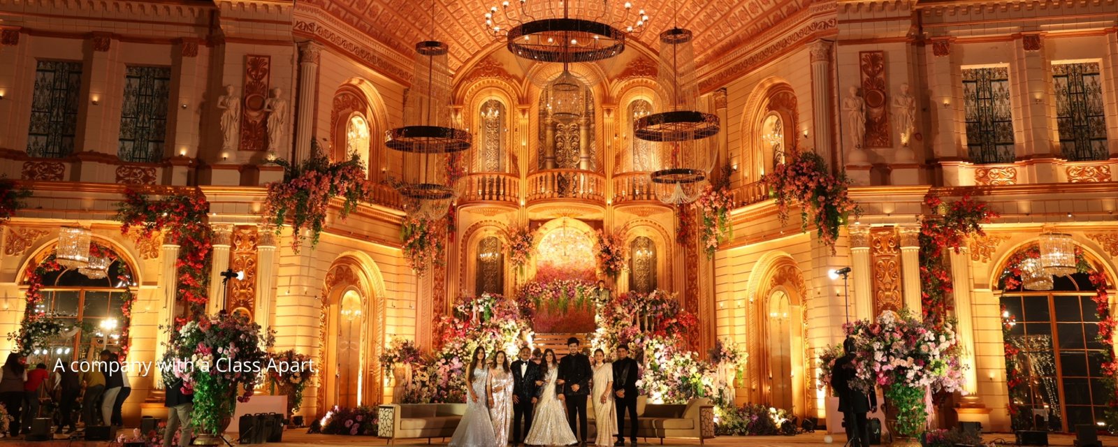 Elegant wedding setup with floral decorations and seating, white chairs and pastel flowers on tables, soft natural lighting, different angle