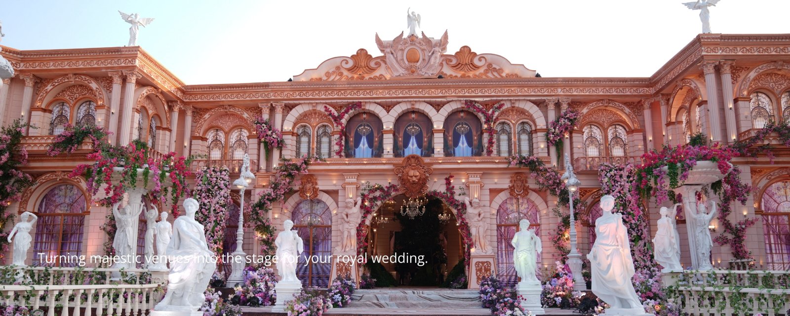 Elegant wedding setup with floral decorations and seating, white chairs and pastel flowers on tables, soft natural lighting, wide angle with guests seating