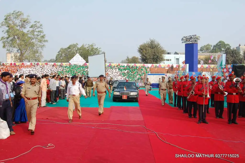 Balloon arch in orange, black, and white colors framing an ITT logo board lit with warm lights